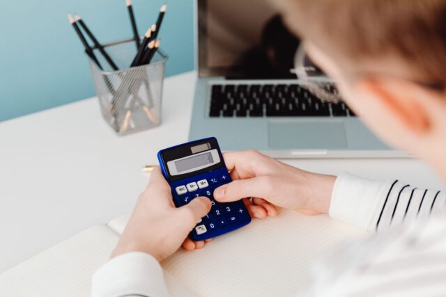 Calculator și caiet cu notițe pe un birou, pentru calculul costului unui obiect